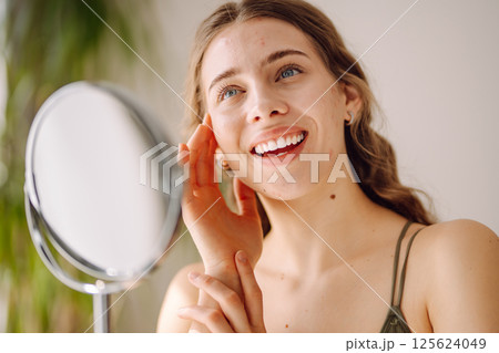 Woman worry about her face when she saw the problem of acne occur by a mini mirror. Pimples, acne 125624049
