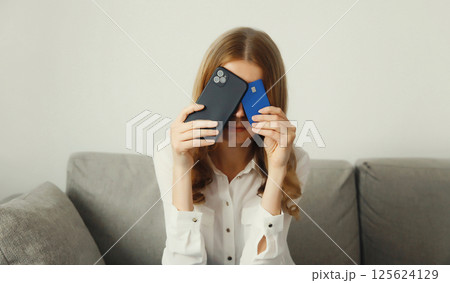 Upset young woman with smartphone, credit bank card, internet fraud, problems with online payments Upset young woman with smartphone, credit bank card, internet fraud, problems with online payments 125624129