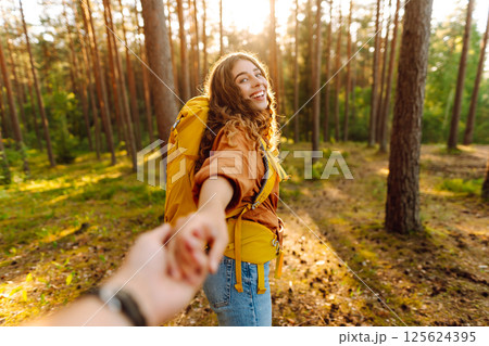 Traveling together. Happy woman holds the boyfriend's hand and walking on the forest. Vacation 125624395