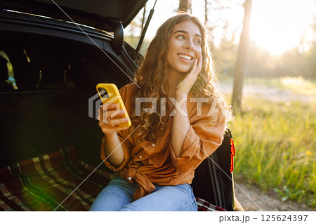 Young woman enjoys a sunny day outdoors while sitting in her car. Travel, weekend, nature, relax Young woman enjoys a sunny day outdoors while sitting in her car. Travel, weekend, nature, relax 125624397