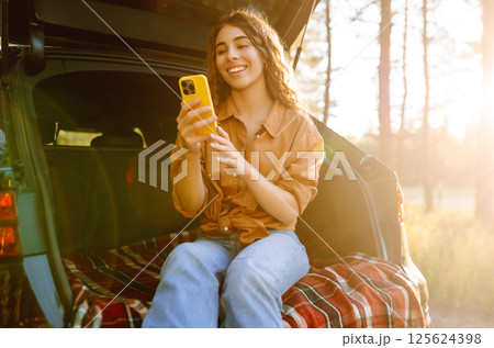 Young woman enjoys a sunny day outdoors while sitting in her car. Travel, weekend, nature, relax Young woman enjoys a sunny day outdoors while sitting in her car. Travel, weekend, nature, relax 125624398