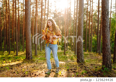 Young woman using mobile application to navigate in autumn forest. Happy tourist trying to find way 125624416
