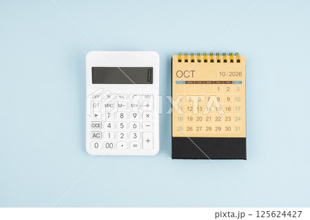 October 2026 desk calendar and calculator on blue background. 125624427