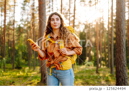 Young woman using mobile application to navigate in autumn forest. Happy tourist trying to find way 125624494