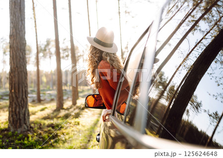 Young woman leaning out of the car window enjoying nature. Road trips summer holidays. Young woman leaning out of the car window enjoying nature. Road trips summer holidays. 125624648