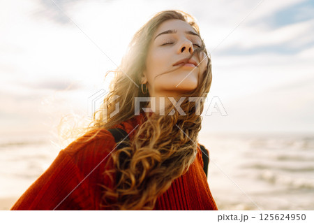 As she walked along the beach, the woman tourist adjusted her backpack, taking in the salty sea air As she walked along the beach, the woman tourist adjusted her backpack, taking in the salty sea air 125624950