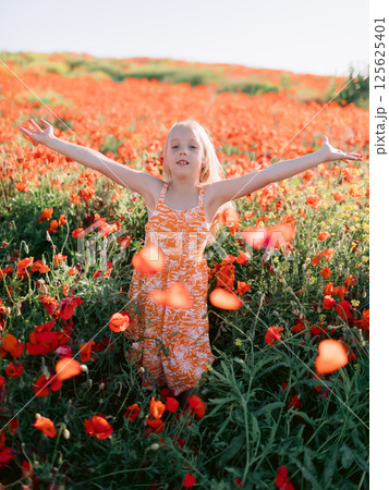 Happy child girl in blooming poppy field, summer day 125625401