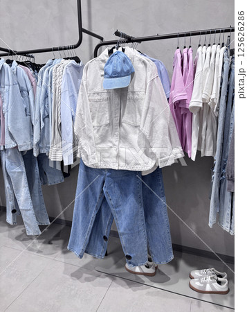 The contemporary clothing boutique features a trendy collection of denim and casual wear hanging on hangers 125626286