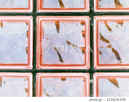 Transparent clear pink glass wall. Decorative block of brick and glass squares. Modern interior design for shower room. Abstract seamless background. 125626346