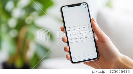 Female hand holding smartphone with calendar app displayed 125626456