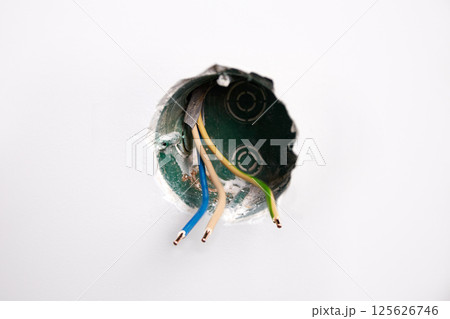 An electrical conduit box is built into the wall with wires sticking out as part of a home renovation 125626746