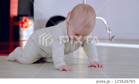 Baby boy moves across floor innocent curiosity leading him on quiet adventure of discovery. Crawling across room little boy begins to explore world innocence and amazement of childhood. 125626765
