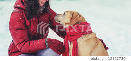 Young happy girl with a Labrador retriever dog are best friends. The girl and dog are outdoors in winter 125627304