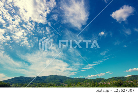 Beautiful blue sky with white fluffy clouds over mountain ridge Beautiful blue sky with white fluffy clouds over mountain ridge 125627307
