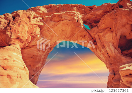 Arch in the rock against colorful sunset sky. Desert nature landscape. Timna Park. Israel Arch in the rock against colorful sunset sky. Desert nature landscape. Timna Park. Israel 125627361