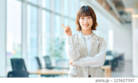 人差し指を立てて案内する笑顔の女性・ビジネスウーマン 人差し指を立てて案内する笑顔の女性・ビジネスウーマン 125627397