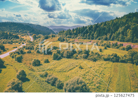 Aerial view of the countryside, country road and cultivated fields on the hills on a sunny spring day Aerial view of the countryside, country road and cultivated fields on the hills on a sunny spring day 125627475
