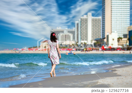 Young woman walking back to camera at sunset on the beach in Tel Aviv, Israel. Solitude Young woman walking back to camera at sunset on the beach in Tel Aviv, Israel. Solitude 125627716