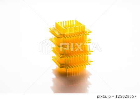 Yellow elements of the children's construction set are laid out on a white background, creating a sense of unity. The plastic pieces of the play set attract attention with their clear shapes. 125628557