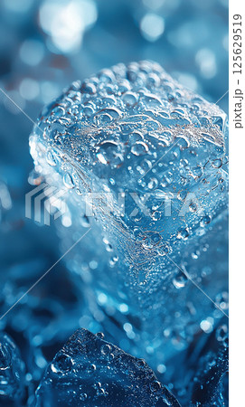 Close-up of a clear ice cube covered in water droplets, creating a chilled, refreshing scene. 125629519