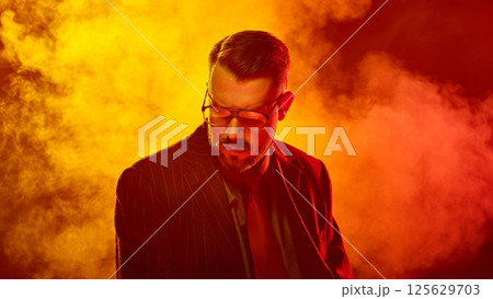 Man in suit lowers head with eyes closed in saturated red light suggesting emotional surrender Man in suit lowers head with eyes closed in saturated red light suggesting emotional surrender 125629703