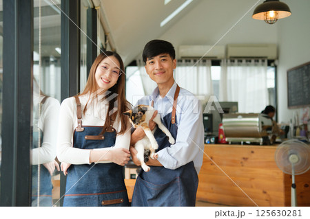 Small business owners enjoying time with a cat in their pet-friendly coffee shop 125630281