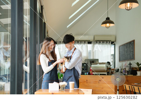 Small business owners enjoying time with a cat in their pet-friendly coffee shop 125630282