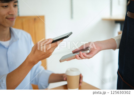 Customer making digital payment at coffee shop using smartphone. Customer making digital payment at coffee shop using smartphone. 125630302