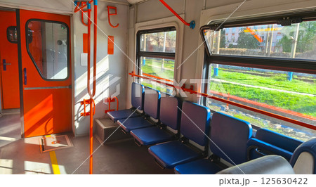 Interior of an empty city train carriage with blue seats and orange handrails. Passenger train. Empty seats in the carriage. Intercity.  125630422