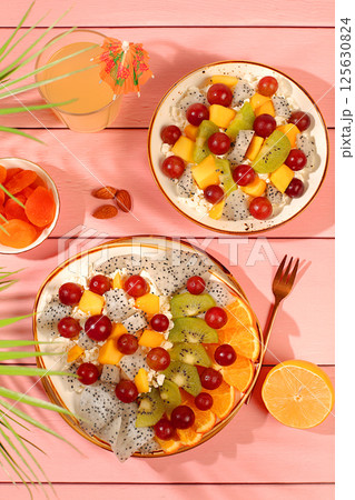 Kitchen background with fruit salads with soft grain cottage cheese, yogurt, dragon fruit, kiwi, mango, oranges, nuts, orange juice and grapes. Healthy light breakfast with ingredients, 125630824