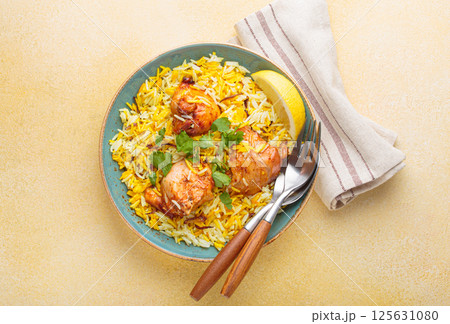 Traditional Indian dish chicken biryani with cilantro and lemon in a bowl top view on beige background 125631080