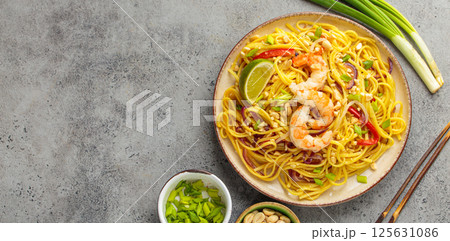Pad thai noodles with shrimps, peanuts and lime on a plate top view, dish of Thailand. Space for text 125631086