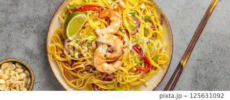 Pad thai noodles with shrimp, peanuts and lime on grey background, dish of Thailand Pad thai noodles with shrimp, peanuts and lime on grey background, dish of Thailand 125631092