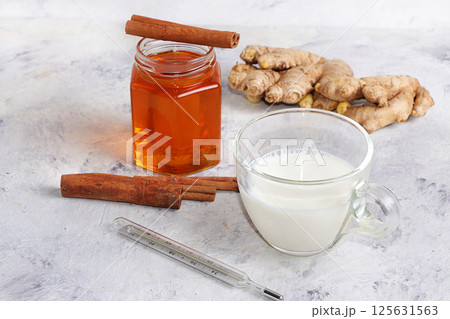A healthy hot milk drink with ginger root, cinnamon sticks, honey, a thermometer, spices for Ayurvedic medicine. The concept of alternative medicine, has a strong anti-inflammatory effect, A healthy hot milk drink with ginger root, cinnamon sticks, honey, a thermometer, spices for Ayurvedic medicine. The concept of alternative medicine, has a strong anti-inflammatory effect, 125631563