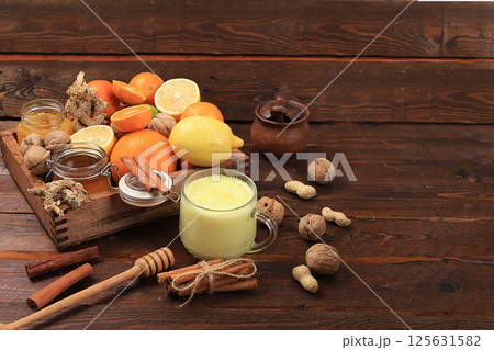 Healthy natural food for flu and colds. Golden turmeric latte and fresh fruit with vitamin C and natural ingredients to strengthen the immune system, protect against viruses, selective focus. Healthy natural food for flu and colds. Golden turmeric latte and fresh fruit with vitamin C and natural ingredients to strengthen the immune system, protect against viruses, selective focus. 125631582