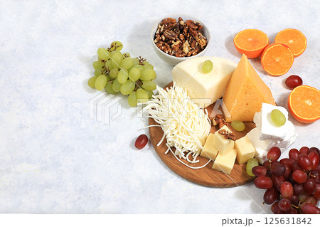 Assortment of different types of cheeses, grapes and nuts, healthy and natural food selection, advertising card or invitation for cafe, shop, menu, selective focus, place for text 125631842