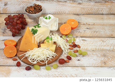 Assortment of different types of cheeses, grapes and nuts on an old wooden background, healthy and natural food selection, advertising card or invitation for cafe, shop, menu, selective focus, place 125631845
