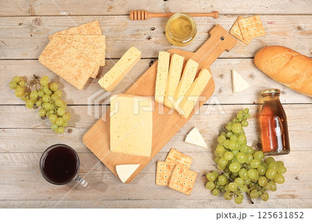 Assortment of different varieties of cheese, red wine, grapes and cracker, the basis of the French diet, healthy and natural food selection, advertising card or invitation to a cafe, shop, menu, 125631852