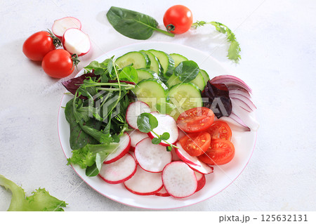 Green vegetable salad with cherry tomatoes, cucumber, radish and fresh arugula, detox diet. Healthy natural breakfast for weight loss, cholesterol and GMO free, selective focus, place for text, 125632131