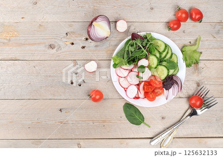 Green vegetable salad with cherry tomatoes, cucumber, radish and fresh arugula, detox diet. Healthy natural breakfast for weight loss, cholesterol and GMO free, selective focus, rustic style, place 125632133