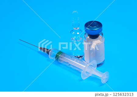 Close-up medical syringe and vials with medicine for injection on blue background 125632313