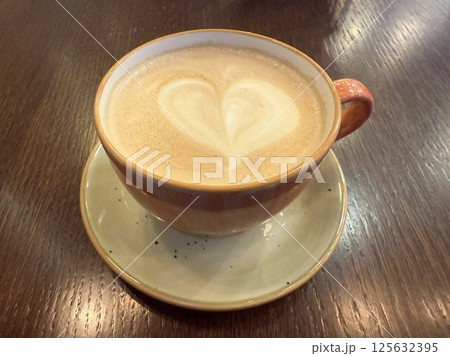 Hot latte art coffee with colored cream on wooden table Hot latte art coffee with colored cream on wooden table 125632395