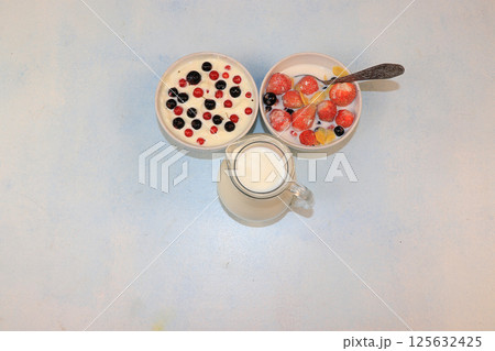 Strawberry yogurt, milk and ripe berries of currants and strawberries on a light background. Delicious healthy breakfast of yogurt and strawberries with copy space, top view, selective focus Strawberry yogurt, milk and ripe berries of currants and strawberries on a light background. Delicious healthy breakfast of yogurt and strawberries with copy space, top view, selective focus 125632425