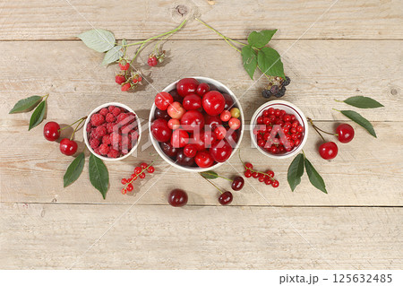 Summer fresh cherries, currants and raspberries on a wooden background with leaves, harvesting in the village, healthy natural food concept, breakfast with ingredients, banner and shop advertisement, 125632485