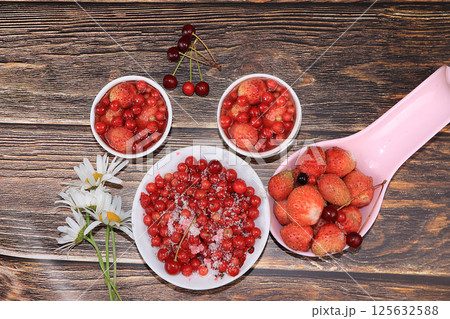 Summer berries of currants and strawberries on a wooden table, top view. Natural berries of currants and strawberries and jam from them in small cups, selective focus, copy space Summer berries of currants and strawberries on a wooden table, top view. Natural berries of currants and strawberries and jam from them in small cups, selective focus, copy space 125632588