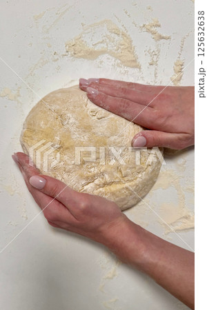 Kneading dough with hands on a floured surface for baking bread, showcasing art of homemade cooking Kneading dough with hands on a floured surface for baking bread, showcasing art of homemade cooking 125632638
