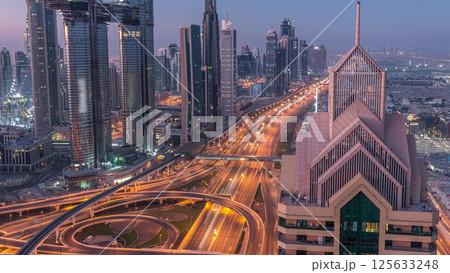 Dubai downtown skyline with tallest skyscrapers and busiest traffic on highway intersection night to day timelapse Dubai downtown skyline with tallest skyscrapers and busiest traffic on highway intersection night to day timelapse 125633248