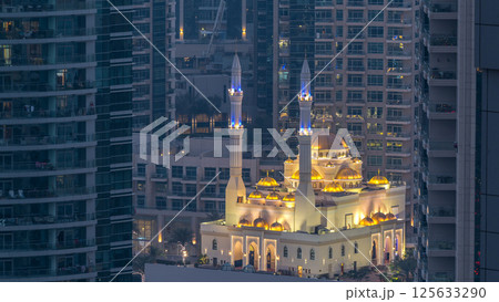 Al Raheem mosque between skyscrapers day to night timelapse on the marina walk in Dubai Marina, Dubai, UAE. 125633290