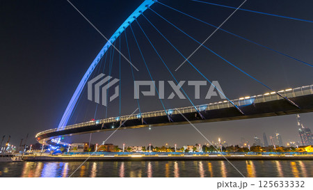 Futuristic Pedestrian Bridge over the Dubai Water Canal Illuminated at Night timelapse hyperlapse, UAE. 125633332