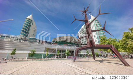 Visitors coming in and out of the Vasco da Gama Shopping mall timelapse hyperlapse, modern towers in the background. Lisbon, Portugal 125633594